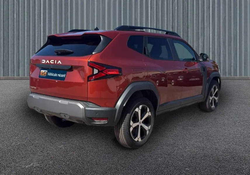Vue 3/4 arrière droite du Dacia Duster orange 2025 avec barres de toit et jantes alliage 18 pouces.