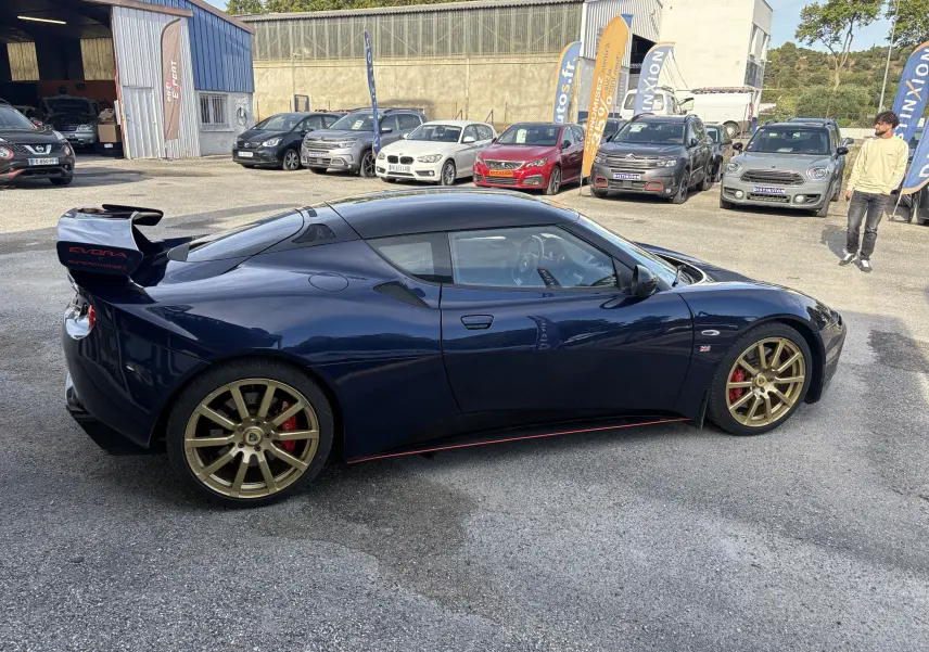 Lotus Evora 3.5 V6 S 2015 en Nightfall blue, vue de profil côté gauche avec jantes dorées et aileron arrière.