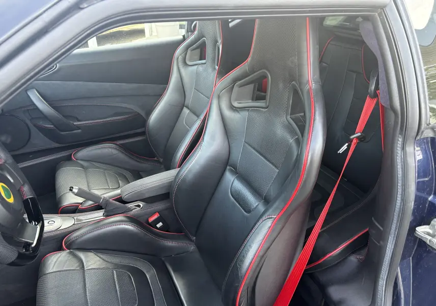 Intérieur de la Lotus Evora 3.5 V6 S 2015 en Nightfall blue, vue côté conducteur sur les sièges sport noirs à surpiqûres rouges.