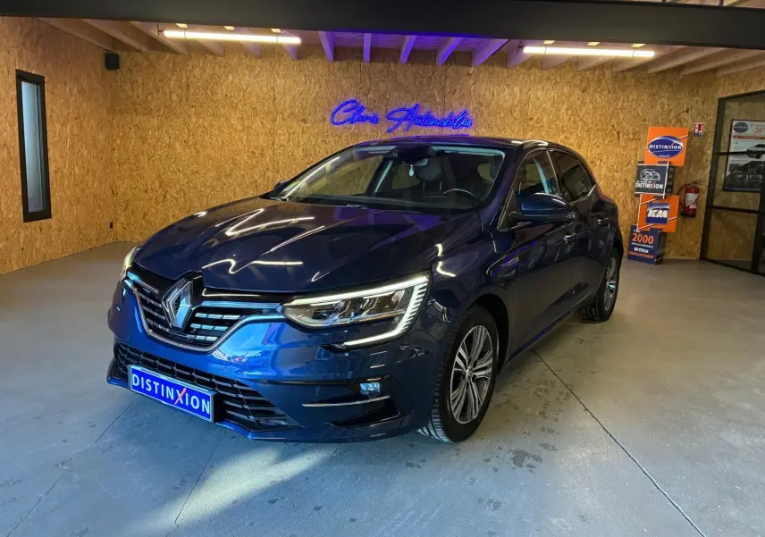 Renault Mégane bleu 3/4 avant droit en intérieur, avec phares LED allumés et jantes alliage bicolores.