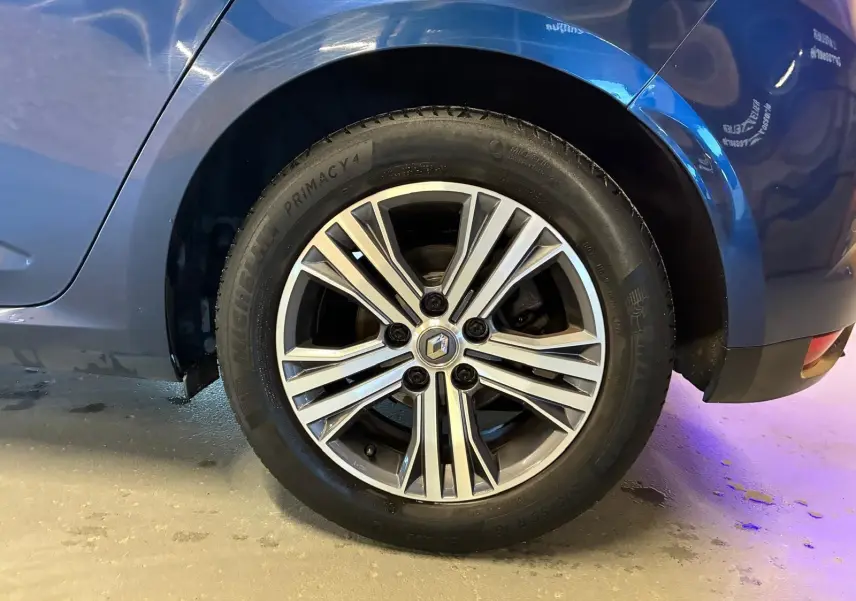 Gros plan sur la roue arrière droite d'une Renault Mégane bleu 2021, avec jante alliage bicolore et logo Renault central.