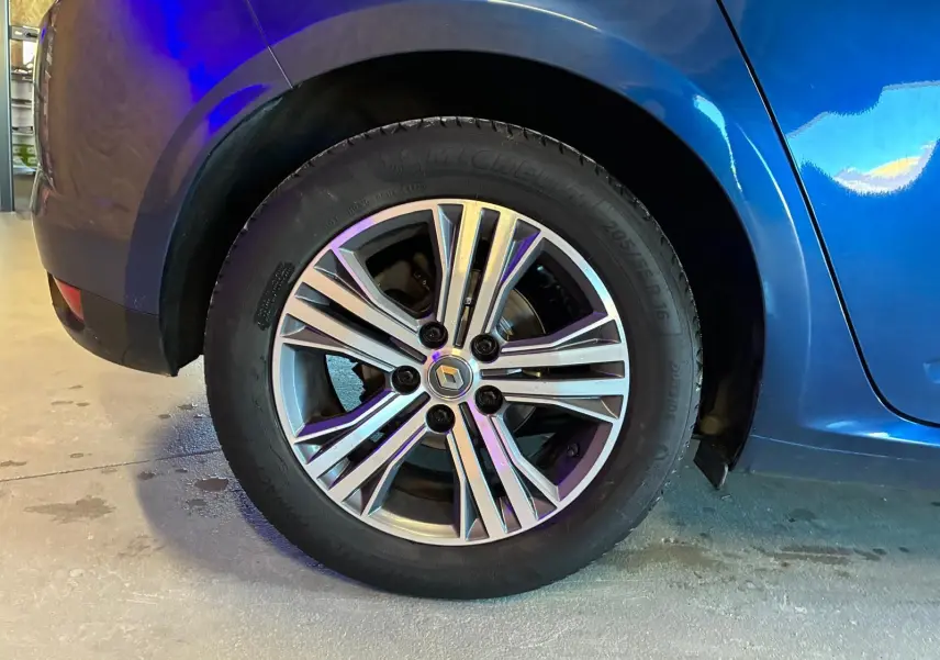 Gros plan sur la roue arrière droite d'une Renault Mégane bleu 2021 avec jante alliage bicolore et logo Renault central.