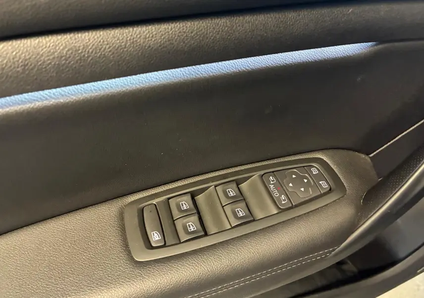 Détail des commandes de lève-vitres et rétroviseurs sur la porte côté conducteur d'une Renault Mégane bleu 2021.