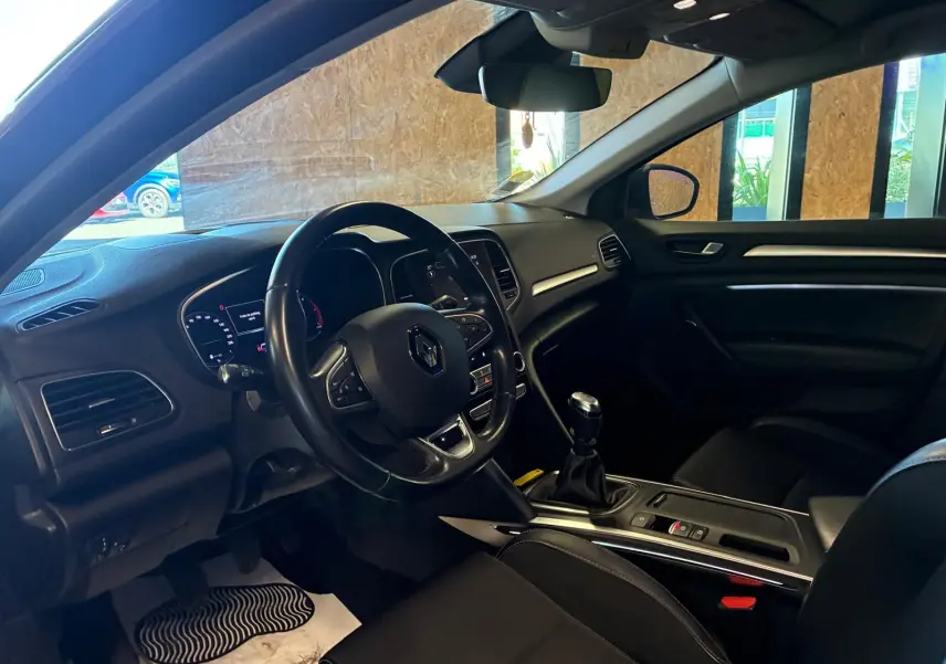 Intérieur avant droit de la Renault Mégane 1.5 DCI 115 Intens 2021, volant cuir, boîte manuelle et tableau de bord moderne.