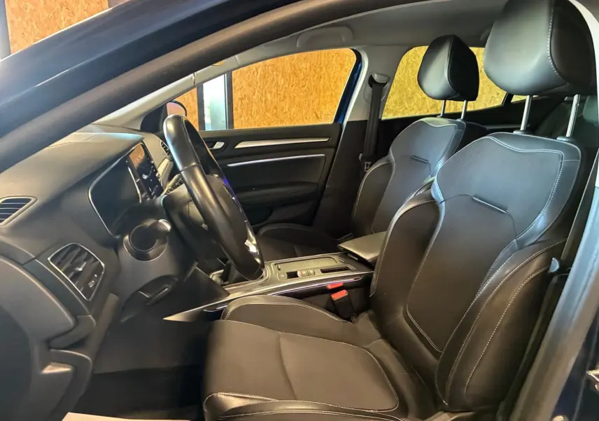 Intérieur avant droit d'une Renault Mégane 1.5 DCI 115 Intens 2021 avec sièges cuir noir et tableau de bord moderne.