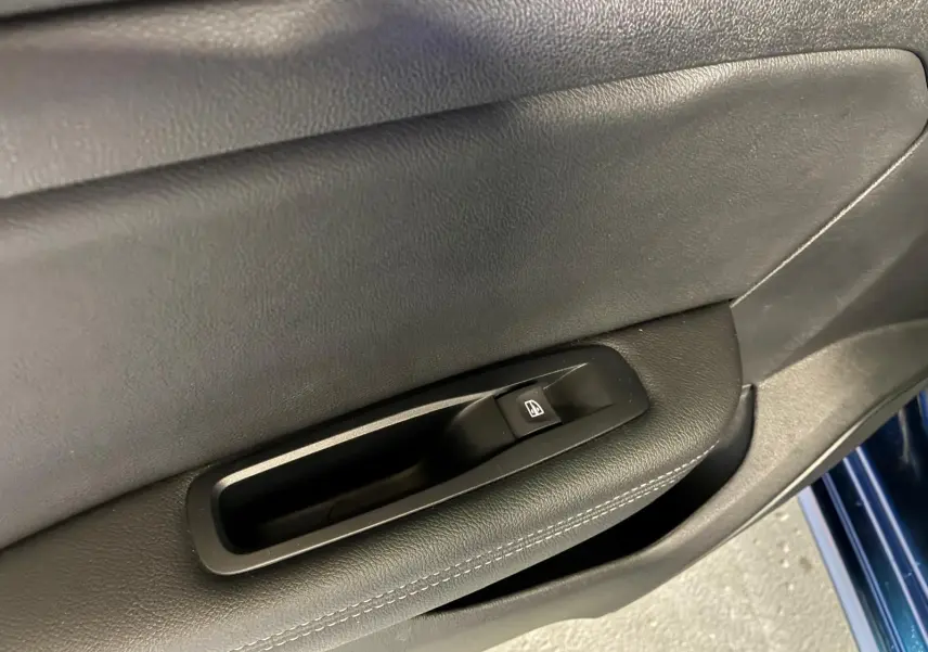 Gros plan sur la commande de lève-vitre côté gauche de la porte d'une Renault Mégane bleu 2021.