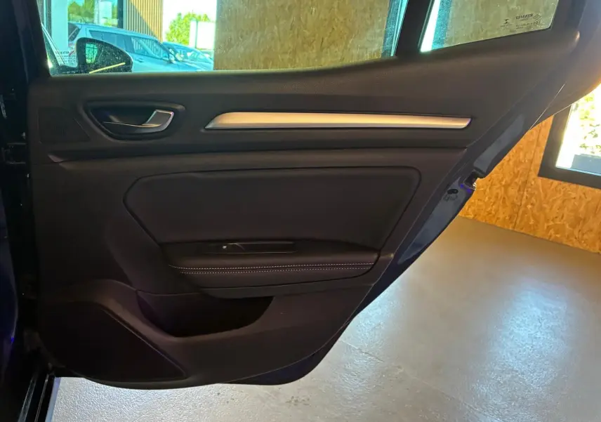Vue intérieure de la porte arrière gauche d'une Renault Mégane 1.5 dCi 115 Intens bleue avec garniture noire et surpiqûres blanches.