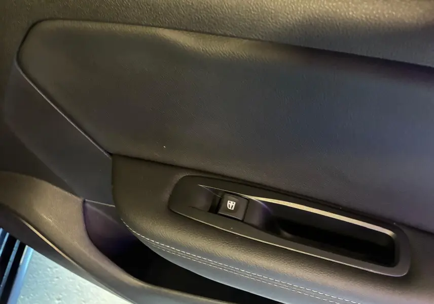 Détail de la commande de lève-vitre sur la porte intérieure côté conducteur d'une Renault Mégane bleu 2021.