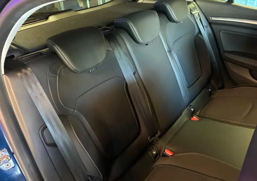 Vue intérieure sur la banquette arrière en cuir et tissu gris noir de la Renault Mégane bleu 2021, avec ceintures et appuie-têtes.