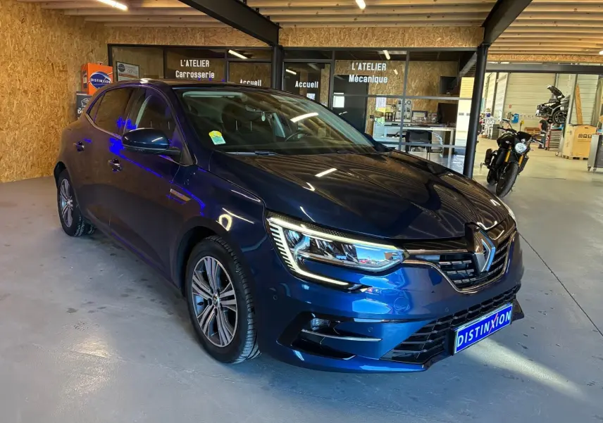 Renault Mégane 1.5 DCI 115 Intens bleu vue 3/4 avant droit dans un garage avec éclairage intérieur.
