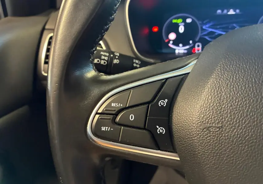 Gros plan sur les commandes de régulateur de vitesse au volant noir d'une Renault Mégane 1.5 DCI 115 Intens 2021.