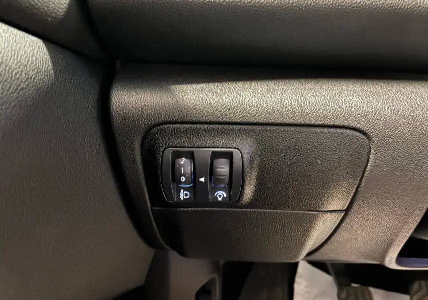Gros plan sur les commandes de réglage des phares et du tableau de bord dans une Renault Mégane 1.5 DCI 115 Intens 2021.