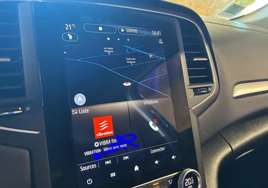 Écran tactile central de la Renault Mégane 1.5 DCI bleu, affichant navigation et radio VIBRA fm, vue intérieure côté passager.