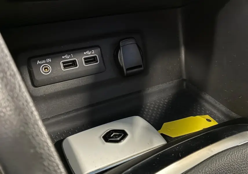 Gros plan sur la console centrale noire avec ports USB, prise auxiliaire et clé Renault blanche dans une Renault Mégane bleu 2021.