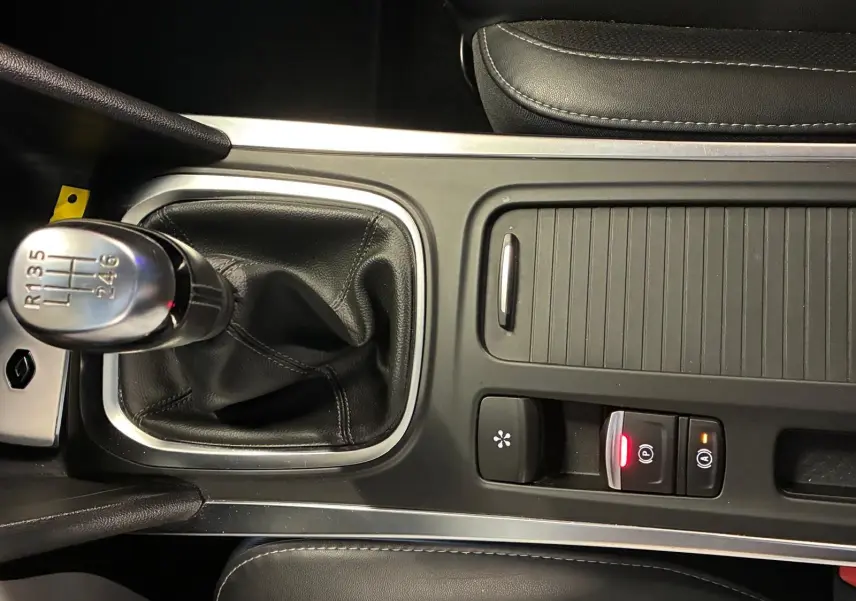 Gros plan sur la console centrale noire d'une Renault Mégane 1.5 DCI 115 Intens 2021 avec levier de vitesse manuel et commandes éclairées.
