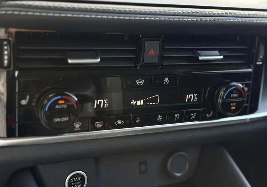 Panneau de climatisation automatique bi-zone noir avec commandes tactiles et bouton Start/Stop dans un Nissan Qashqai 2025.