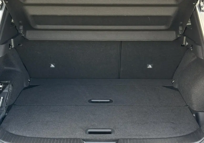 Coffre spacieux du Nissan Qashqai gris argent 2025 avec hayon électrique ouvert, plancher modulable et intérieur noir.