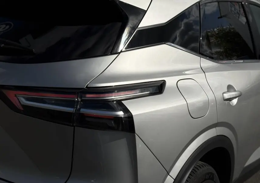 Vue arrière côté gauche du Nissan Qashqai gris argent 2025 avec feux arrière LED effilés et hayon électrique.