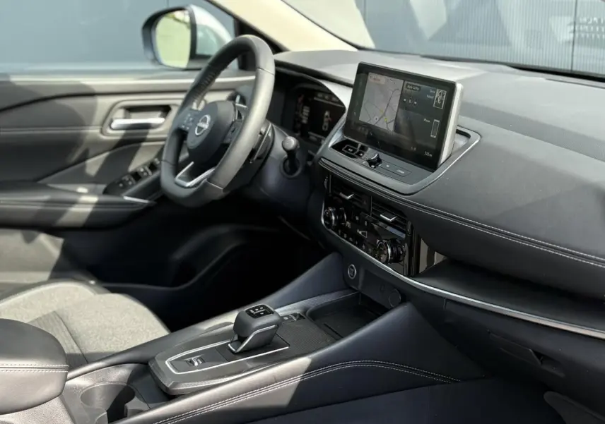 Intérieur du Nissan Qashqai 2025 vu côté conducteur, avec tableau de bord noir et écran tactile central.