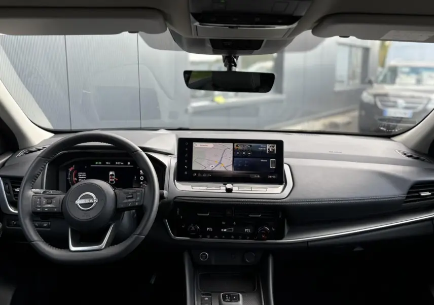 Intérieur du Nissan Qashqai 2025 vu de face, tableau de bord noir avec écran tactile et volant cuir multifonctions.