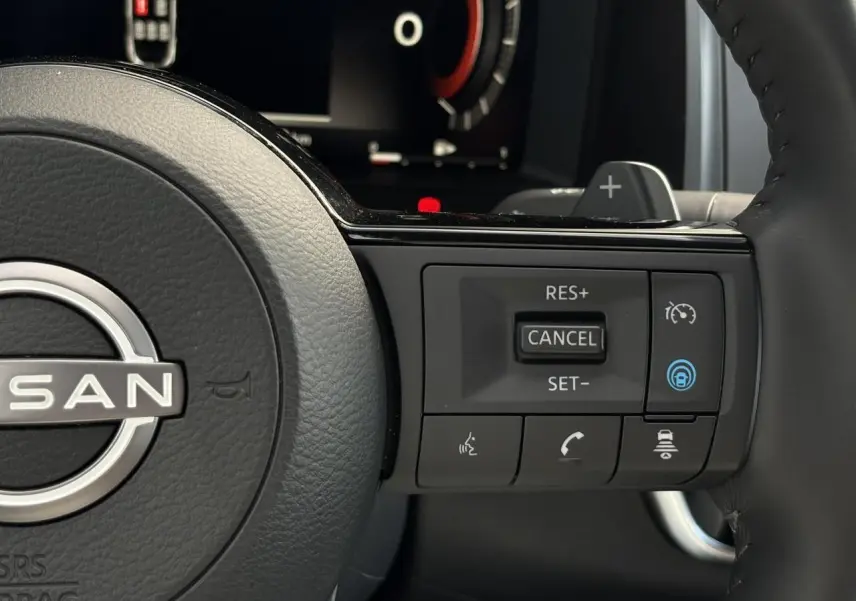 Gros plan sur le volant cuir noir du Nissan Qashqai 2025, avec commandes de régulateur et assistance active visibles