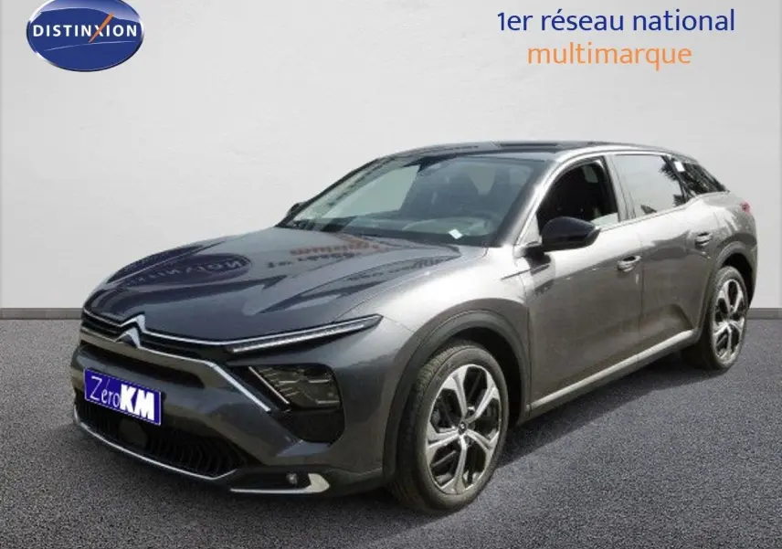 Vue 3/4 avant d'une Citroën C5 X gris platinium métal avec jantes bi-ton et calandre distinctive moderne.