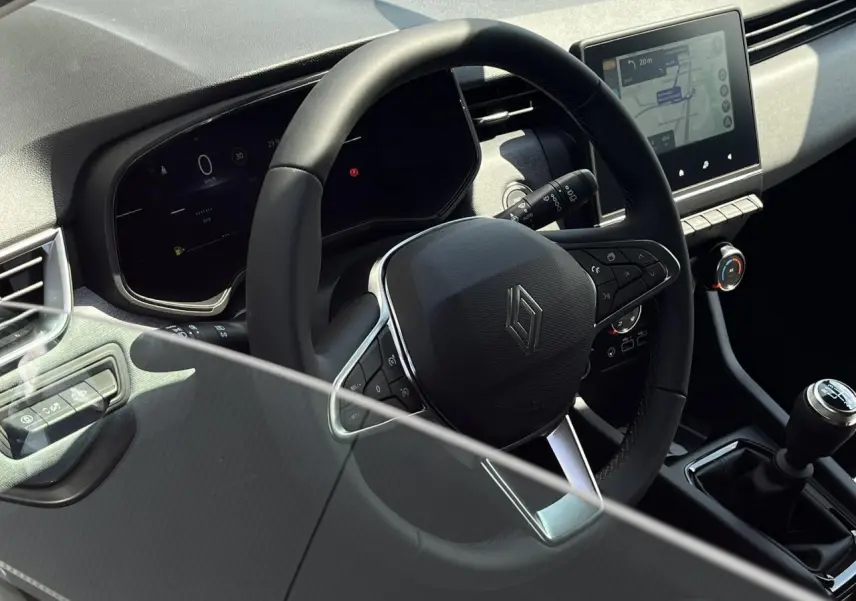 Vue intérieure rapprochée du volant multifonction et de la console centrale avec écran tactile de la Renault Clio blanche.