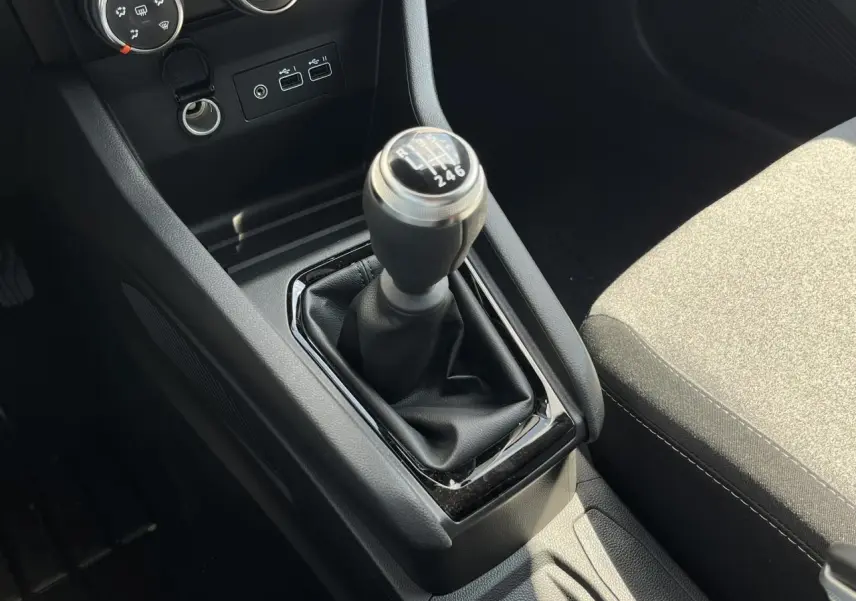 Gros plan sur la commande de boîte manuelle noire et la console centrale de la Renault Clio 2025, intérieur tissu gris.