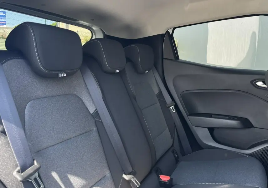 Vue côté droit de l'habitacle arrière de la Renault Clio 2025, sièges tissu gris foncé avec surpiqûres blanches.