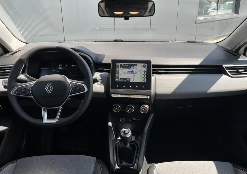 Vue intérieure avant de la Renault Clio 2025, tableau de bord moderne avec écran tactile et volant multifonction noir.