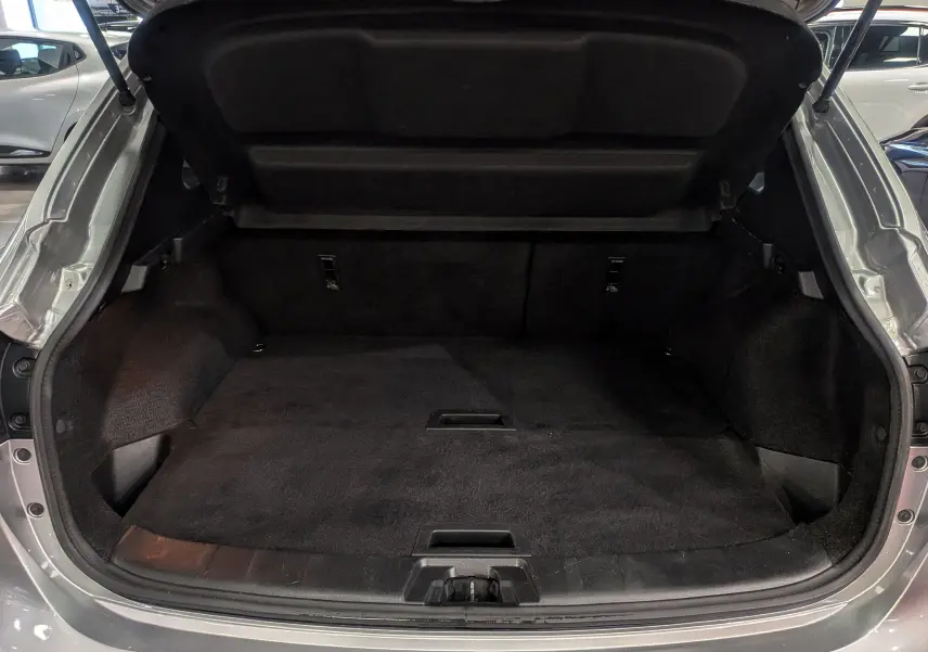 Coffre ouvert d'un Nissan Qashqai gris perle 2018, vue arrière montrant un espace de chargement propre et spacieux.