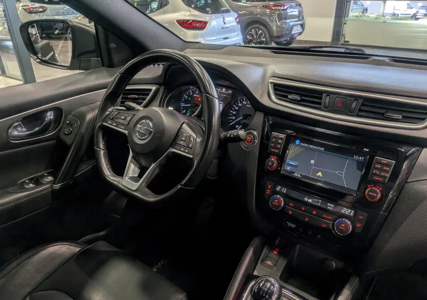 Vue intérieure côté conducteur du Nissan Qashqai 1.2 DiG-T 2018 avec tableau de bord noir et écran tactile de navigation.