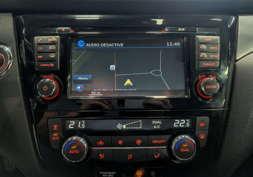 Tableau de bord du Nissan Qashqai 2018 avec écran de navigation et commandes climatisation en vue frontale rapprochée.