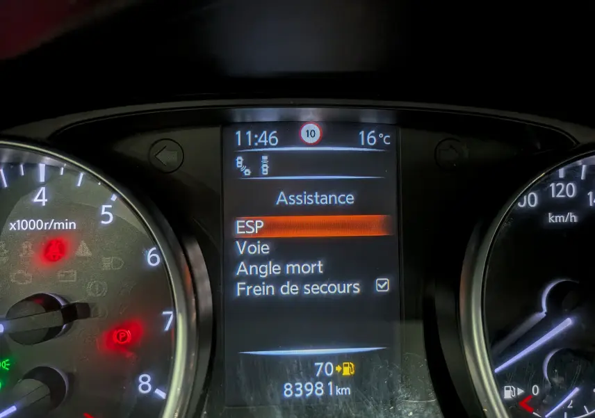 Tableau de bord du Nissan Qashqai gris perle 2018 montrant l'écran d'assistance et les compteurs analogiques.