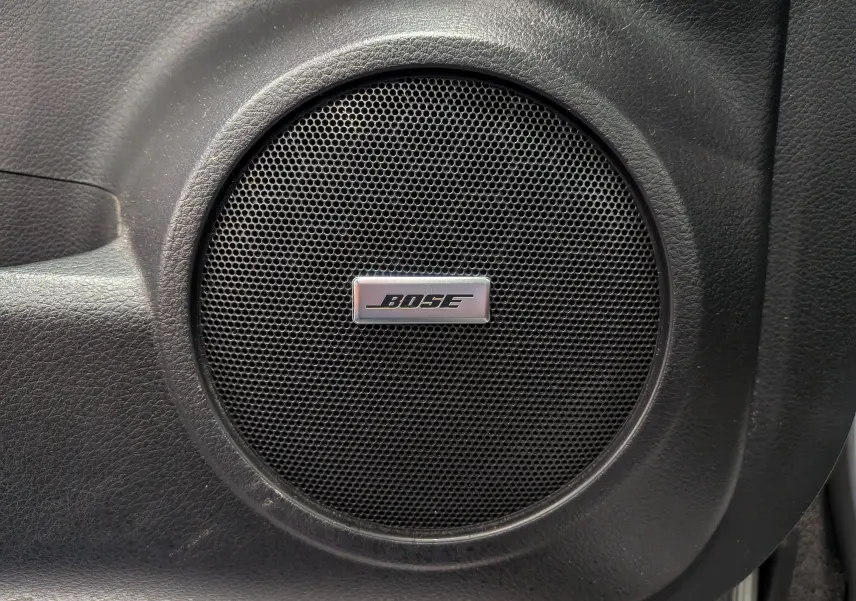 Gros plan sur l'enceinte Bose intégrée dans la porte intérieure noire du Nissan Qashqai 2018 gris perle.