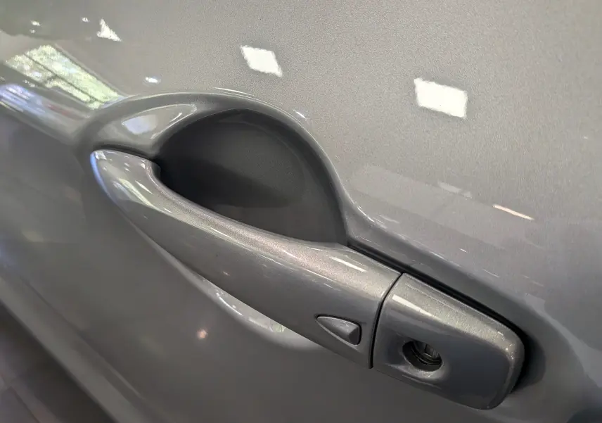 Poignée de porte gris perle du Nissan Qashqai 2018 1.2 DiG-T 115 CH TEKNA+ en gros plan sur la portière côté droit.