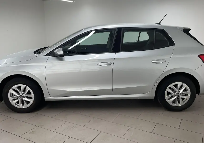 Profil côté gauche d'une Skoda Fabia 2025 gris argent, finition Selection avec jantes alliage et vitres teintées.