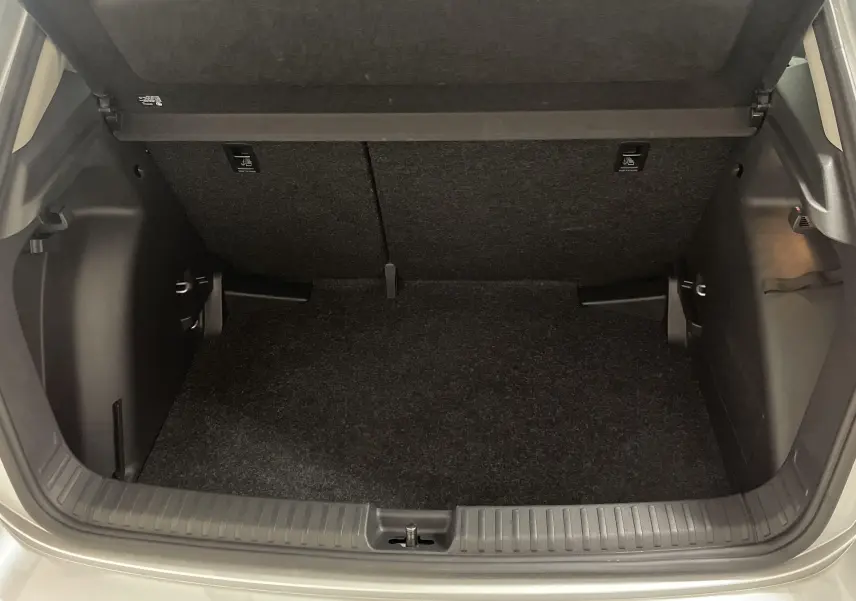 Coffre ouvert d'une Skoda Fabia gris argent, vue arrière montrant l'espace de chargement vide et propre.