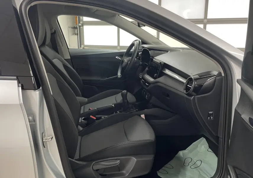 Intérieur avant droit d'une Skoda Fabia gris argent 2025, sièges tissu noirs et tableau de bord moderne.