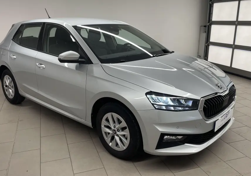 Vue 3/4 avant droite d'une Skoda Fabia gris argent 2025 avec phares LED et calandre noire chromée.