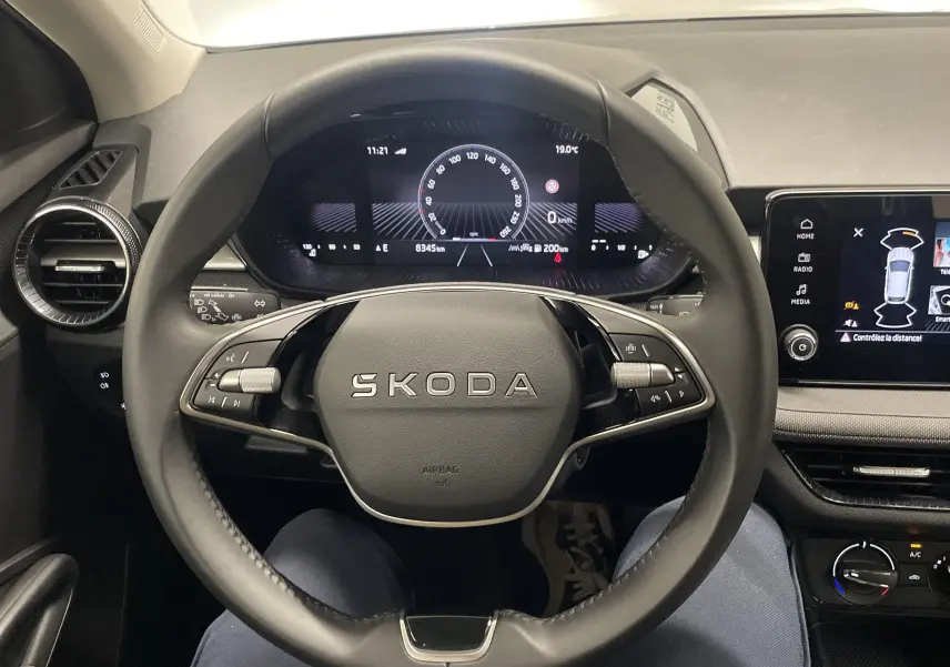 Vue intérieure centrée sur le volant SKODA Fabia 2025, tableau de bord digital et écran tactile multifonction.