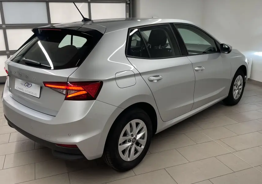 Vue 3/4 arrière droite d'une Skoda Fabia gris argent avec feux arrière allumés dans un garage intérieur.