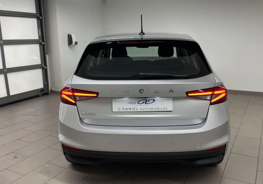 Vue arrière d'une Skoda Fabia gris argent 2025 avec feux allumés et radars de stationnement visibles.
