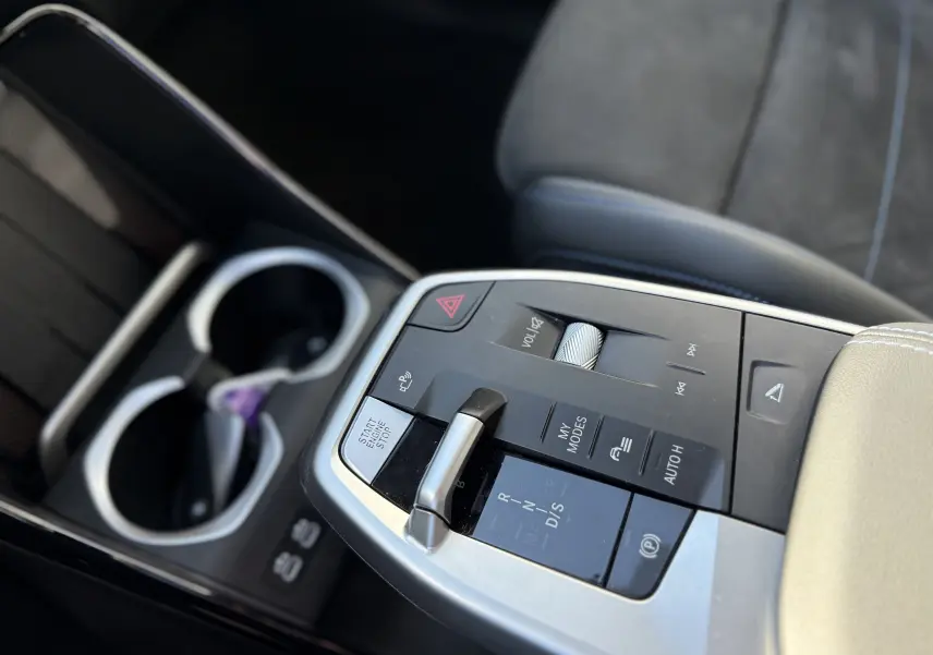 Gros plan sur la console centrale de la BMW X1 20D blanc minéral, montrant le levier de vitesses et les commandes multimédia.