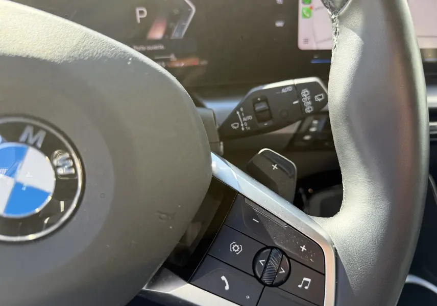 Gros plan sur le volant cuir noir de la BMW X1 20D 163CH M SPORT 2025 avec commandes multifonctions et palettes au volant.