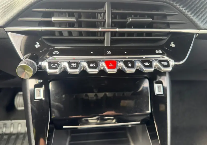 Vue rapprochée du tableau de bord noir du Peugeot 2008 2024, avec rangée de boutons argentés et écran tactile éteint.