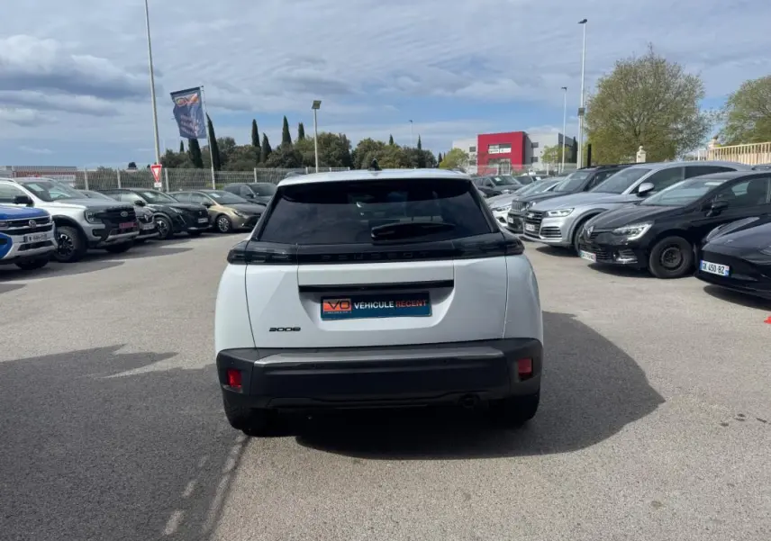 Vue arrière d’un Peugeot 2008 blanc 2024 avec barres de toit et jantes alliage 17 pouces, stationné en extérieur.