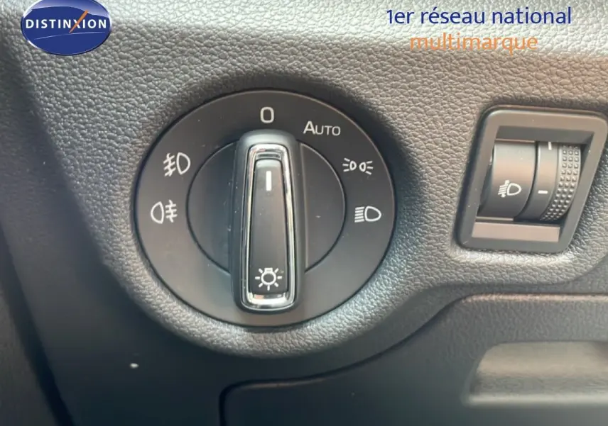Gros plan sur la commande des phares du Skoda Scala blanc glacier, avec molette de réglage et bouton d'intensité lumineuse.