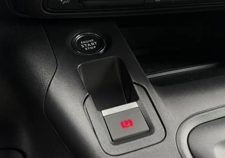 Gros plan sur le bouton de frein de stationnement électrique et démarrage moteur du Peugeot Rifter gris acier.