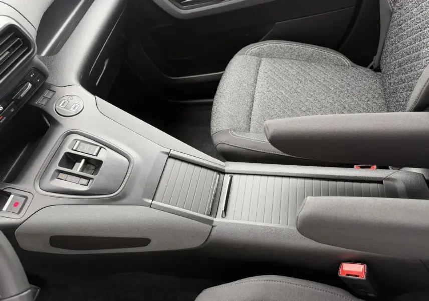 Vue intérieure centrée sur la console centrale et les sièges avant gris tissu du Peugeot Rifter 2026.